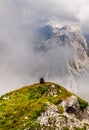 Young woman summerÃÂ hiker with backpack resting on hill onÃÂ steep slopes, panoramic peaks andÃÂ mountains withÃÂ cloudy fog valleys